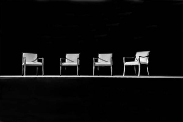 Four empty chairs on a stage