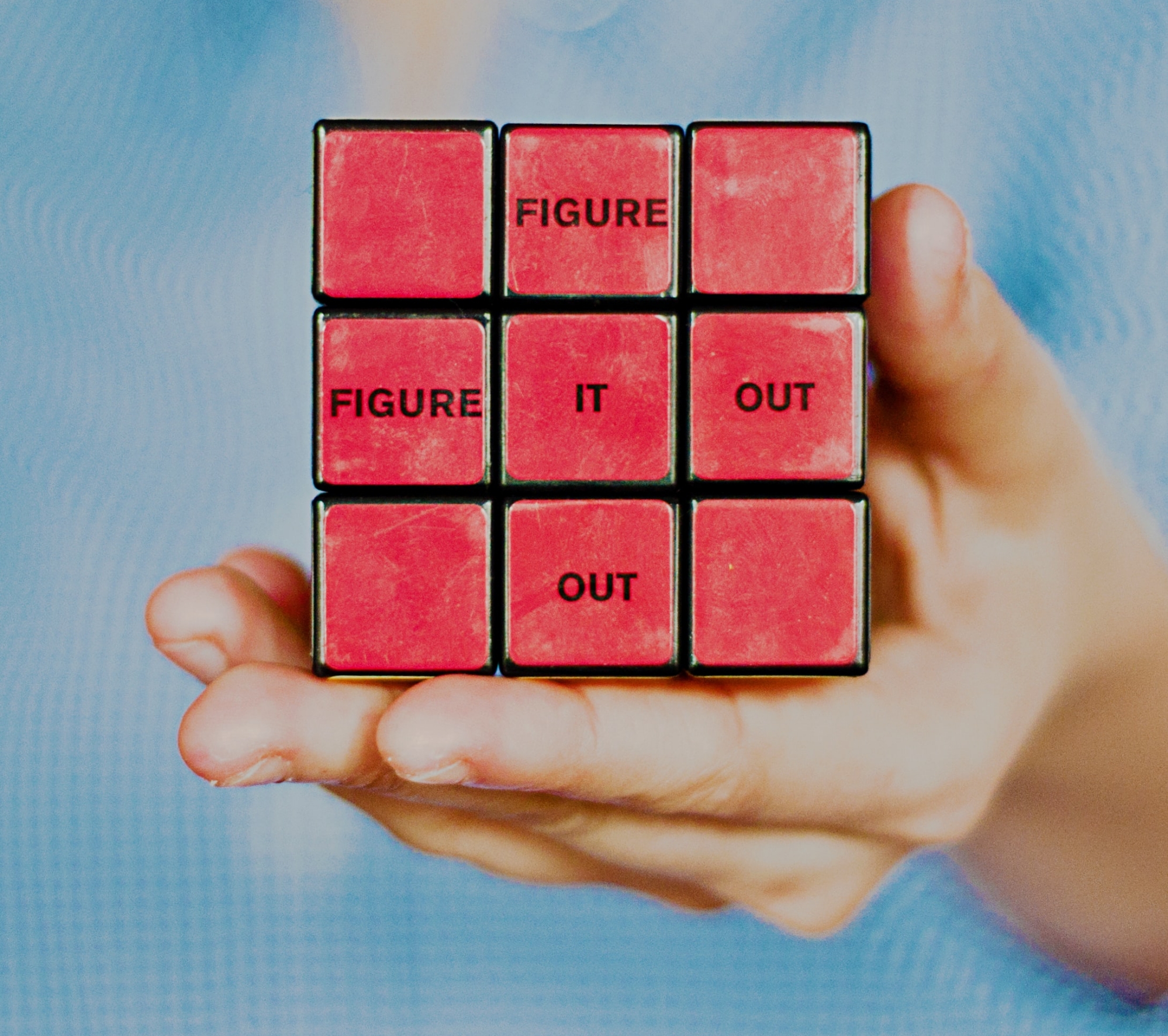 Hand holding a Rubi's cube that says "Figure It Out"