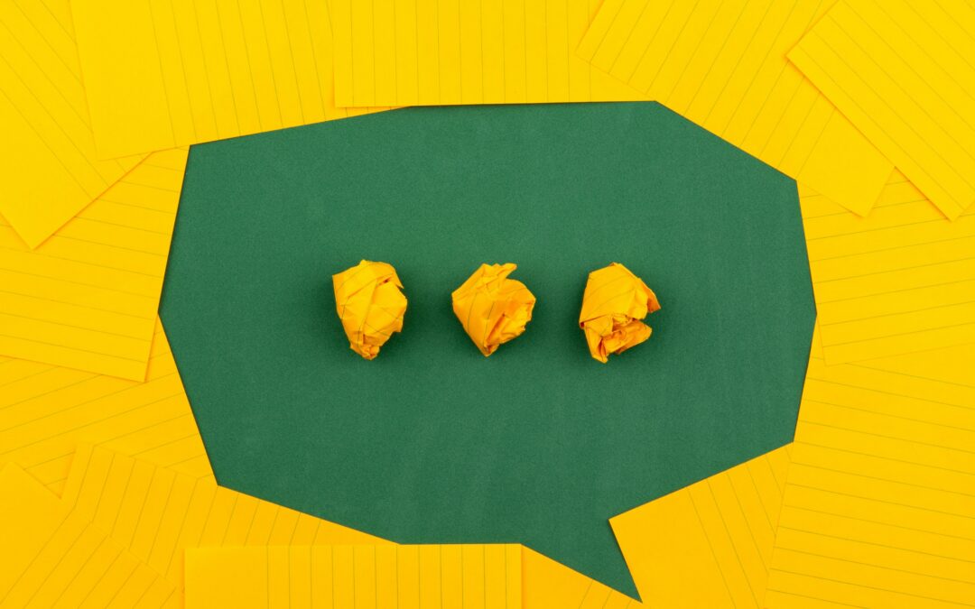 orange sheets of paper lie on a green school board and form a chat bubble with three crumpled papers