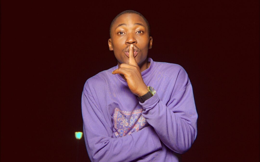 Black man holding a finer to his lips making a "Shhhh" sign