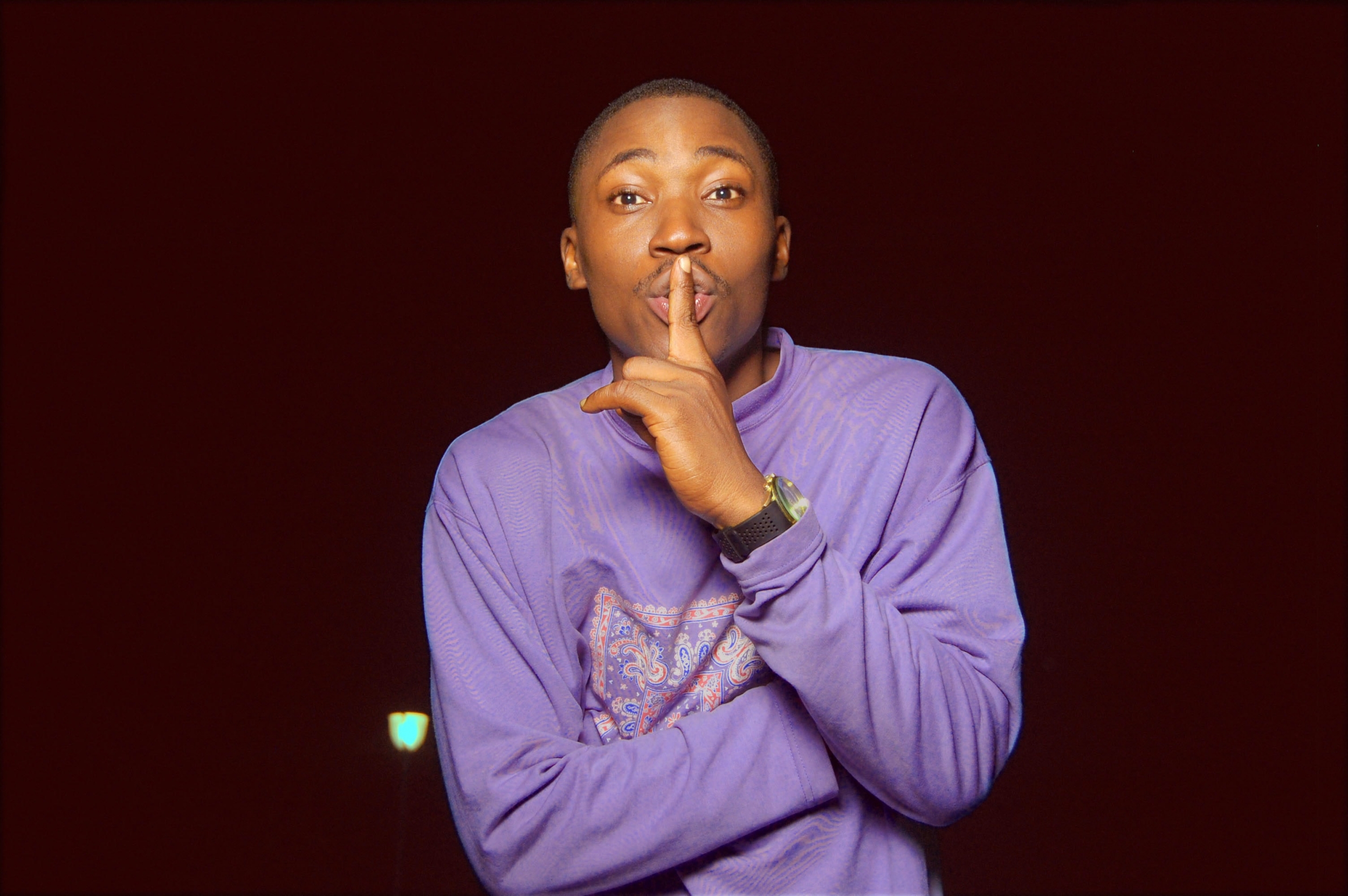 Black man holding a finer to his lips making a "Shhhh" sign