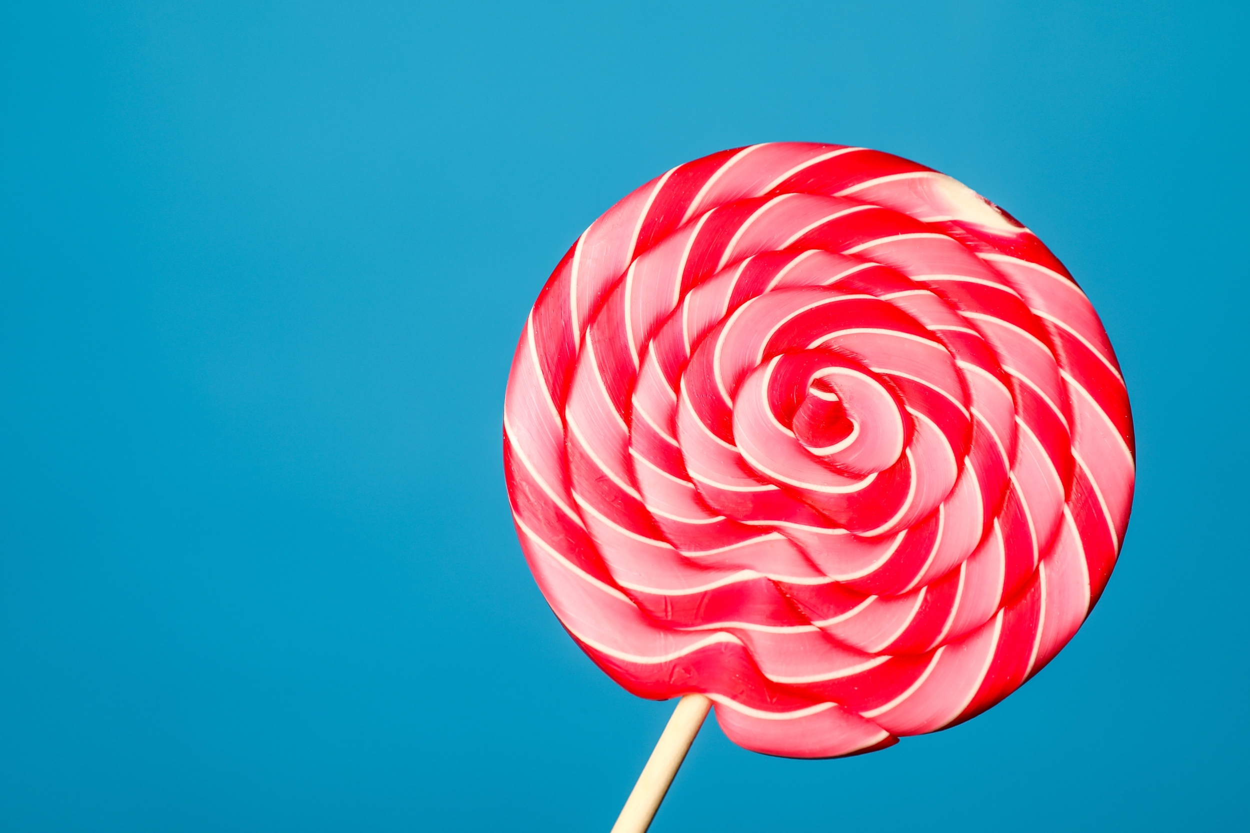 Red and pink striped lollipop on a turquoise background