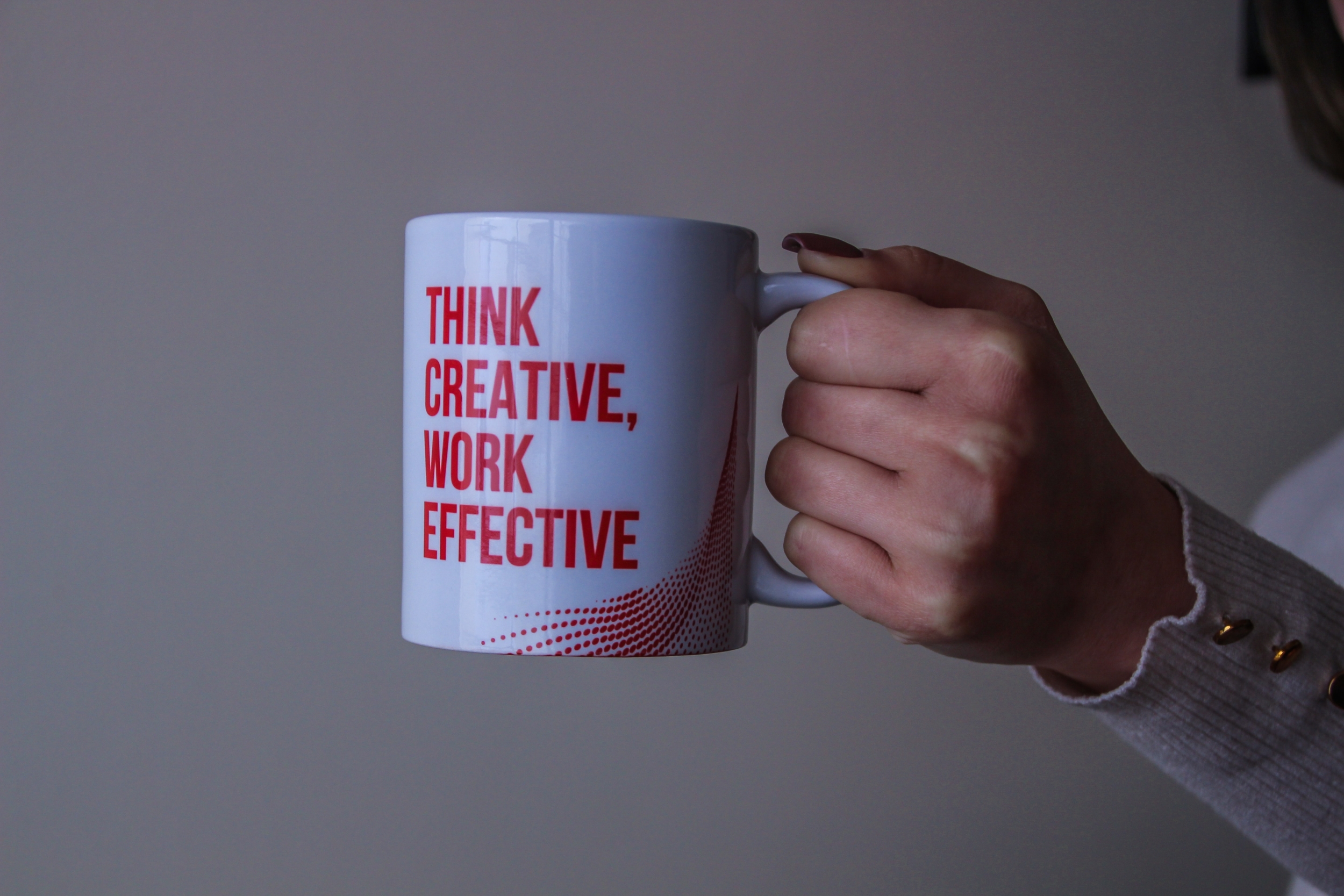 White coffee mug with "Think Creative. Work Effective" written in red block letters