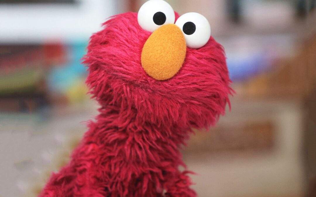 Photo of Elmo, a red hairy monster muppet with an orange nose