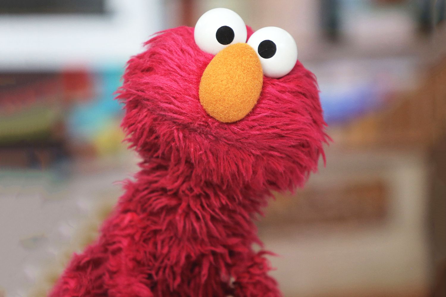 Photo of Elmo, a red hairy monster muppet with an orange nose
