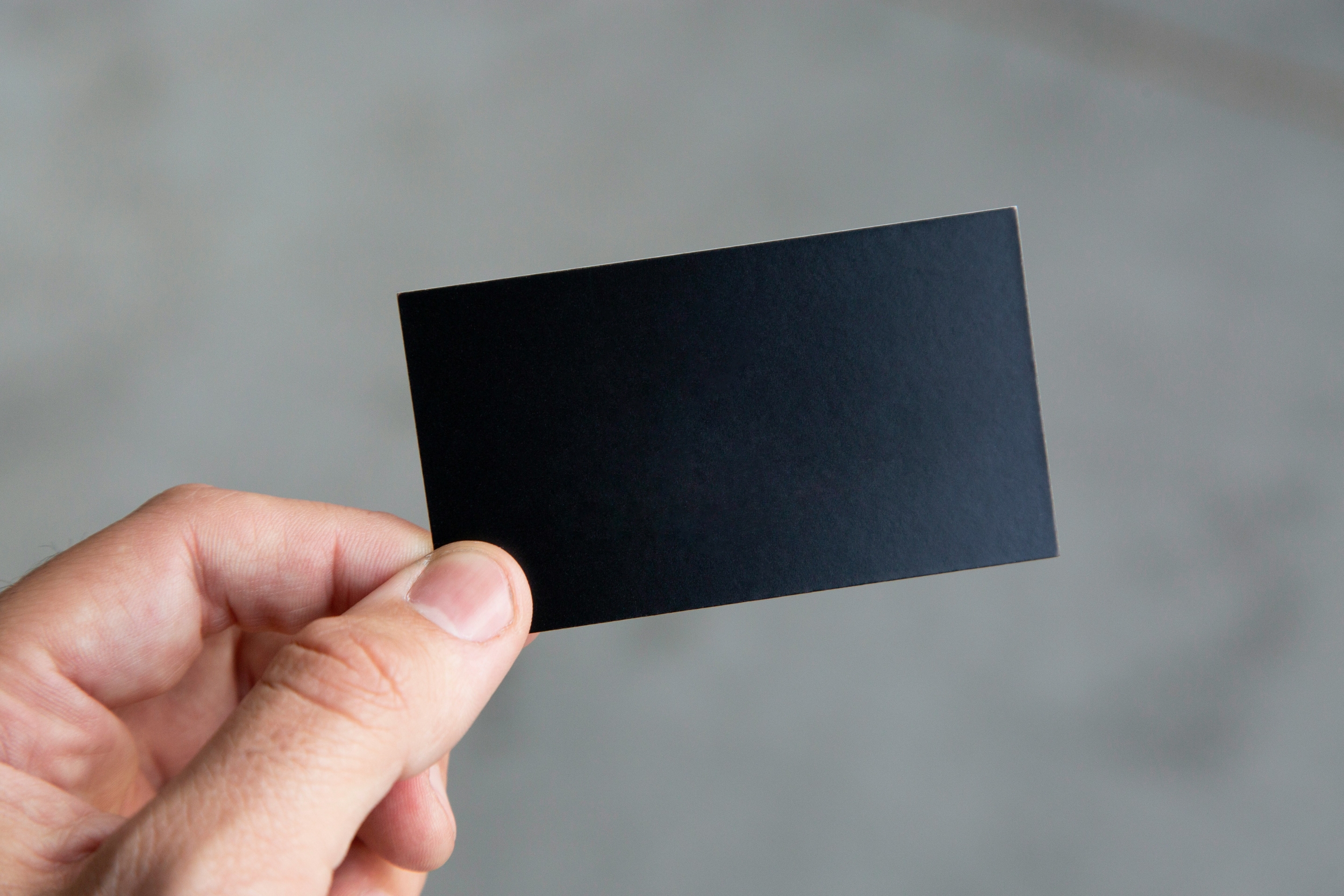 Hand holding a blank black business card