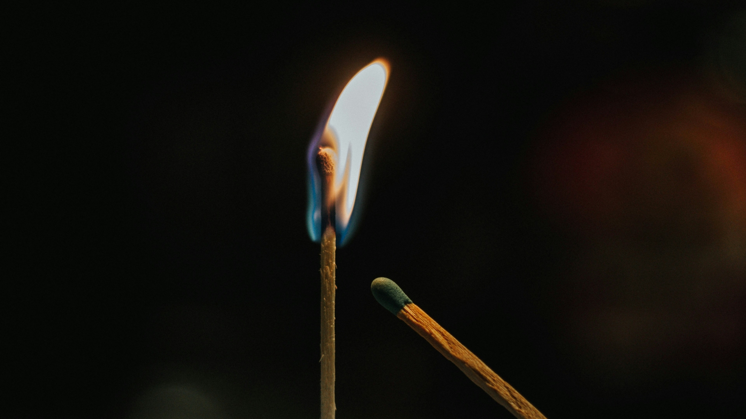 An unlit match leaning towards a lit match
