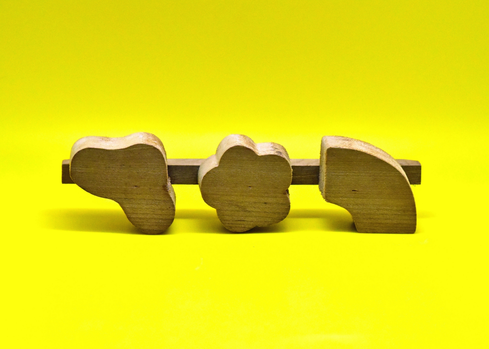 Three wooden puzzle pieces on a yellow background
